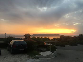 Cars on road against sky at sunset