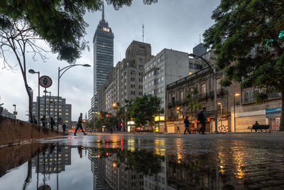 Reflection of buildings on puddle at street in rainy season