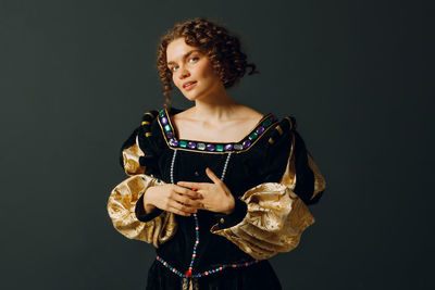 Portrait of young woman standing against black background