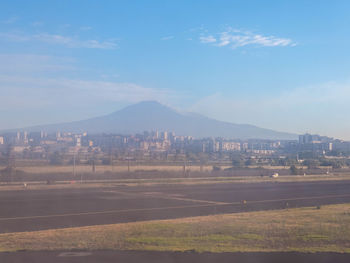 Road by buildings against sky in city