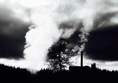 Low angle view of silhouette trees against cloudy sky