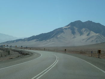 Road by mountains against clear sky