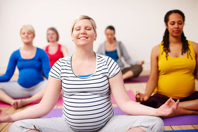 Smiling pregnant women meditating at studio