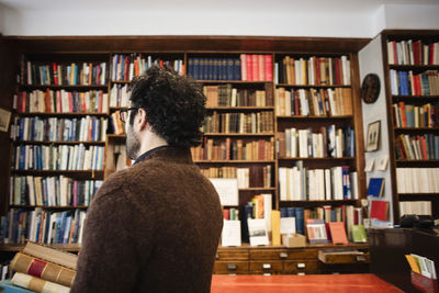 Man with books against bookshelves in library