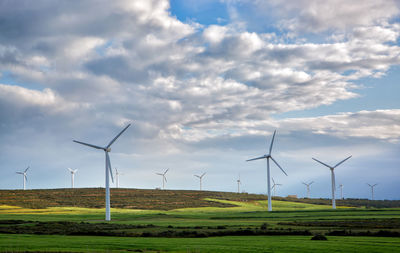 Windmills on field against sky