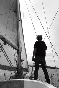 Rear view of man sailing on sea against sky
