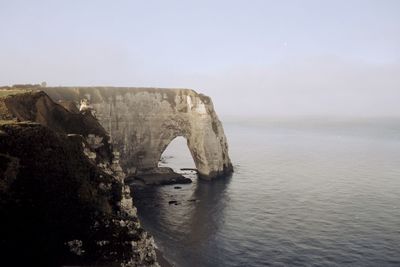 Rock formation in sea against sky