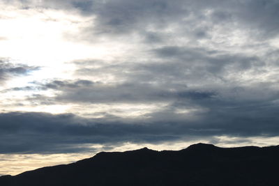 Low angle view of silhouette mountains against dramatic sky