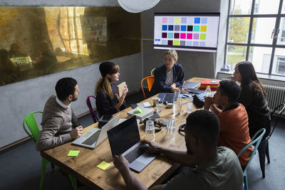 Female entrepreneur explaining strategy of product with colleagues at desk in conference room