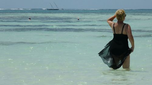 Rear view of young woman standing at beach