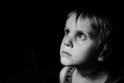 Close-up portrait of cute boy against black background