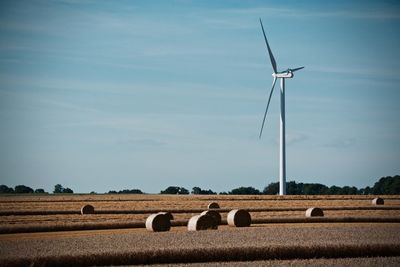 Hay bales and windmills against sky