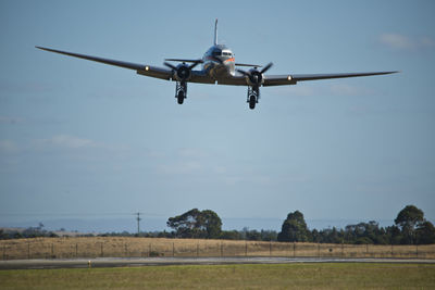 Low angle view of airplane flying against clear blue sky