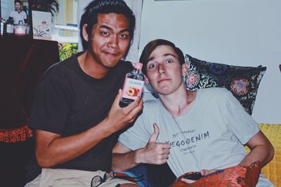 Portrait of handsome young man holding camera while sitting at home