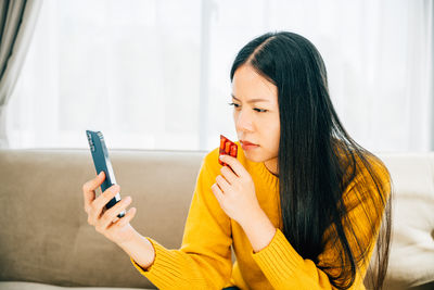 Young woman using mobile phone at home