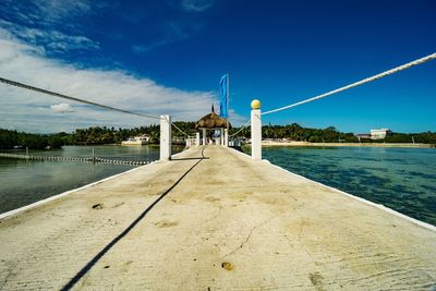 Pier over lake against blue sky