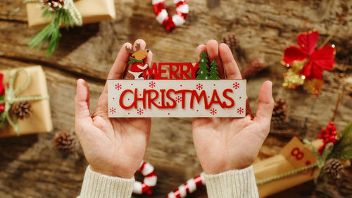 Hand holding merry christmas text on presents background