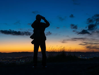 Silhouette man photographing against sky during sunset