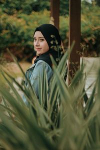 Portrait of smiling young woman by plants