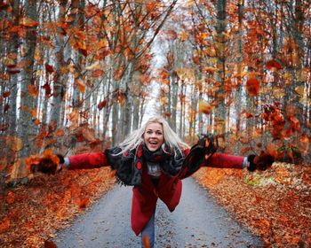 Portrait of smiling young woman in forest during autumn