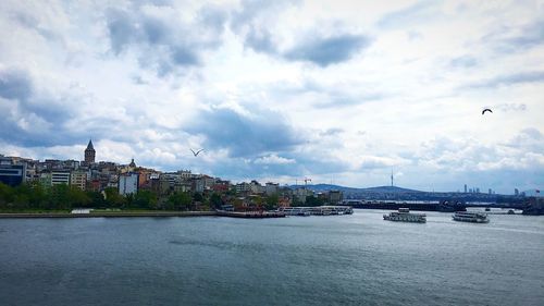 View of buildings by river against cloudy sky