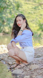 Side view of a young woman sitting on land