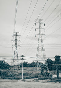 Low angle view of electricity pylon on field against sky