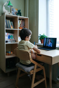 Side view of woman using laptop at home