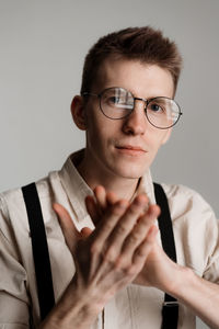 Close-up portrait of young man wearing eyeglasses against white background