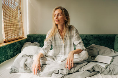 Portrait of young woman sitting on bed at home