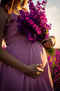 Midsection of woman holding pink flower