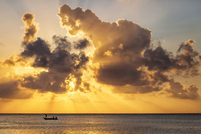 Silhouette people in boat on sea against sky during sunset