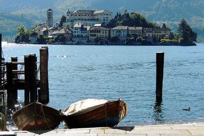 Wooden posts in sea against buildings in city