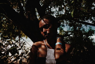 Low angle view of young woman against tree