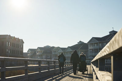 Rear view of people walking on buildings in city against clear sky