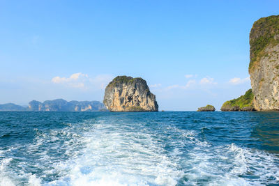 Rocks in sea against blue sky