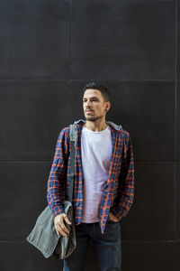 Man wearing shirt standing against wall