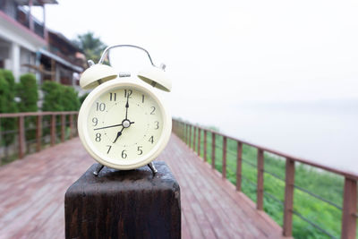 Close-up of clock on railing against sky
