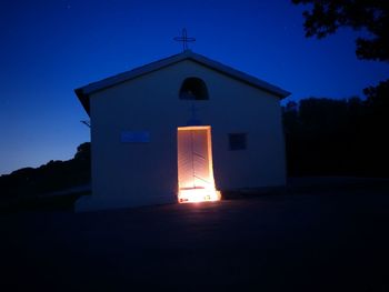 Illuminated church against clear blue sky at night