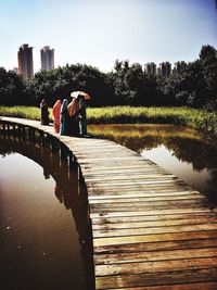 Rear view of woman by lake against clear sky