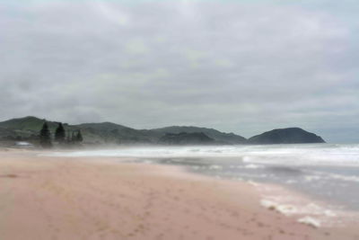 Scenic view of beach against cloudy sky