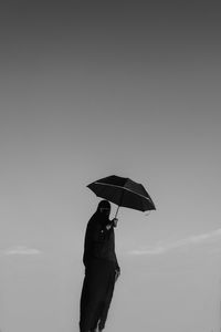 Man holding umbrella standing against sky during rainy season