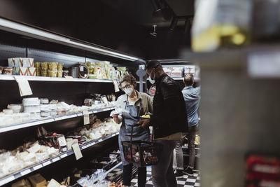 Female owner helping male customer to do shopping at store during pandemic