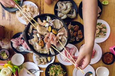 Bbq barbecue eating. people grilling  pork, meal, shellfish and shrimp with wooden chopsticks.