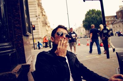 Young man smoking cigarette at sidewalk cafe