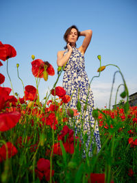 Portrait of young woman standing amidst flowers