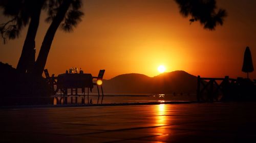 Silhouette built structure in front of sea at sunset