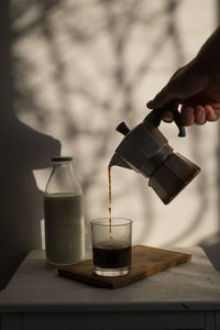 Close-up of hand pouring coffee in cup on table