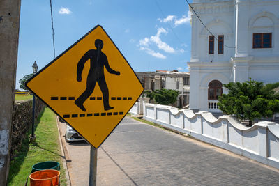 Road sign by building against sky