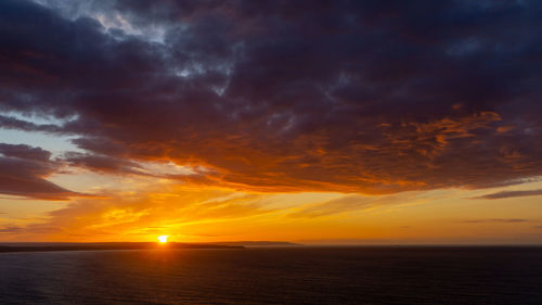 Scenic view of sea against dramatic sky during sunset